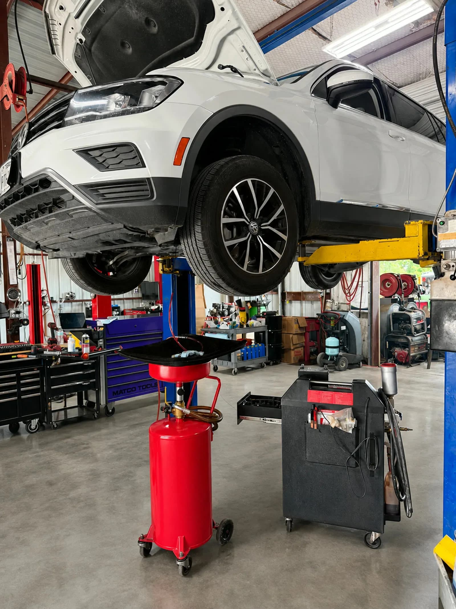 SUV on a lift at Quality Mechanics with transmission fluid exchange equipment staged below